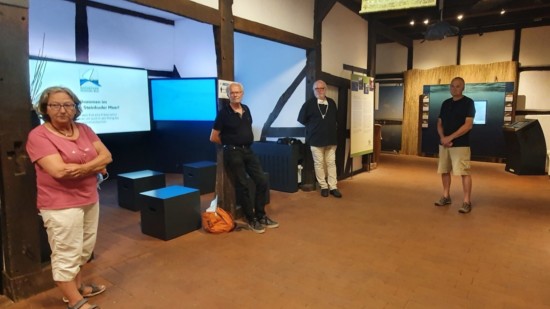 Eine Frau und drei Männer stehen in einem Ausstellungsraum des Infozentrums
