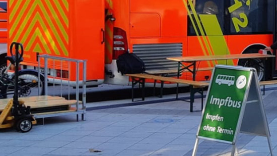 Ein grünes Schild mit der Aufschrift: Impfbus - Impfen ohne Termin steht vor einem Feuerwehrwagen