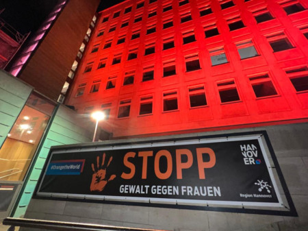 Orange beleuchtetes Regionshaus zum Orange Day 2023 mit Banner: STOPP Gewalt gegen Frauen!